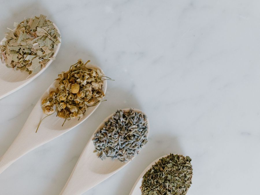 Dried herbs and flowers on wooden spoons