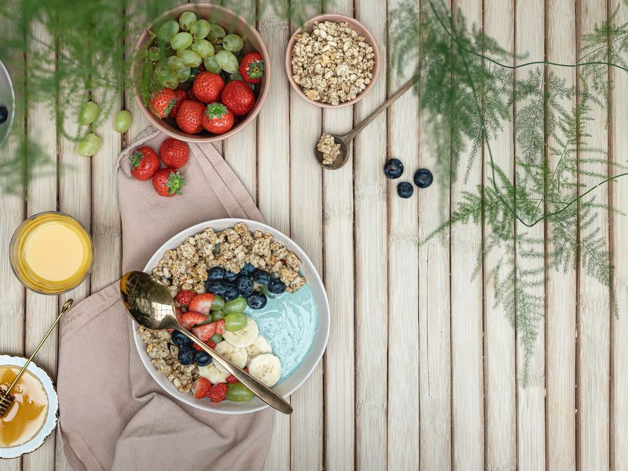 A bowl of fruit, granola and yoghurt on a wooden table